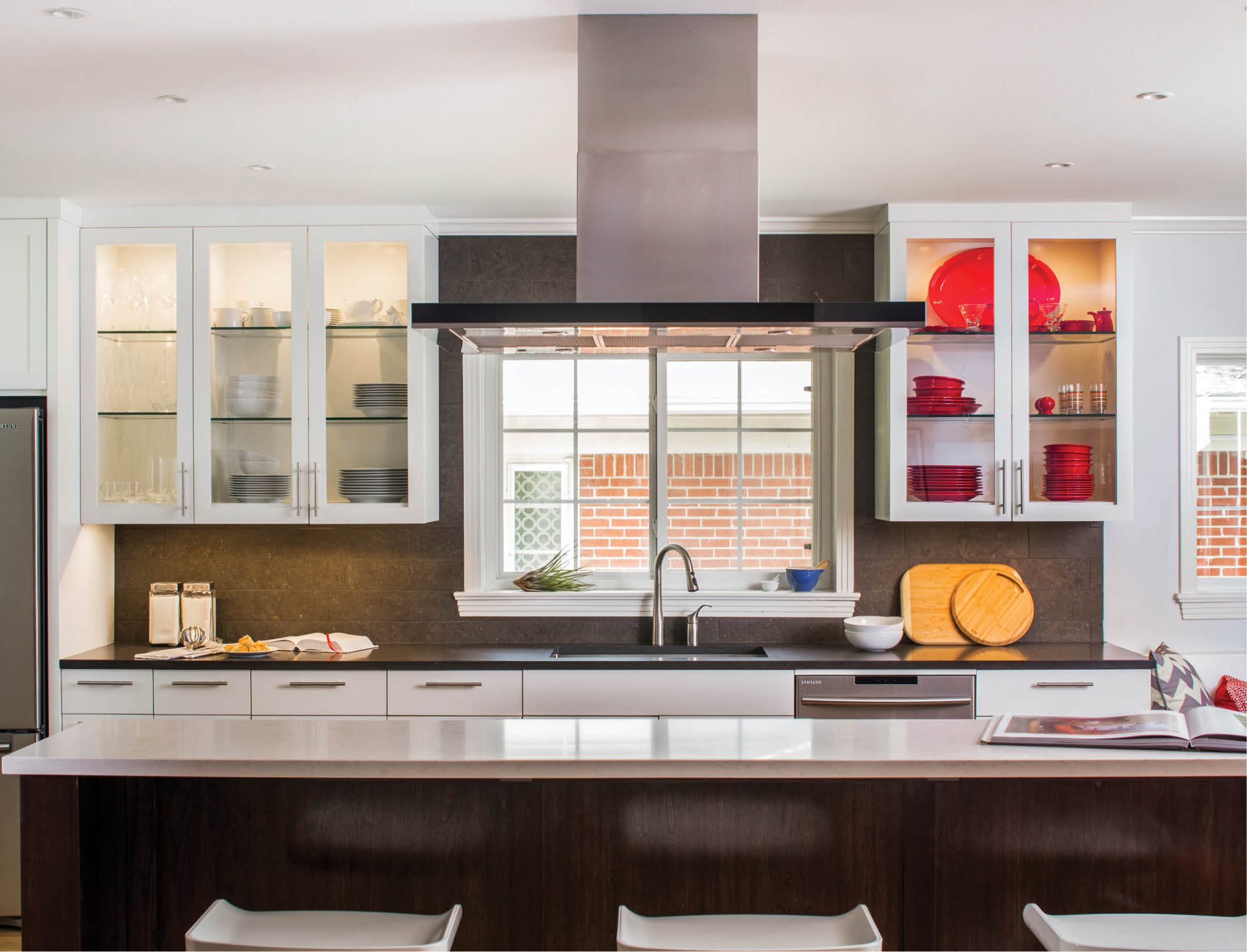 Dressed in walnut cabinetry with a light grey Caesarstone counter, the island provides a dramatic contrast to the white shaker style cabinetry and dark grey Caesarstone counters wrapping the perimeter of this new kitchen. Work by CG&S Design-Build. Photo: Tre Dunham