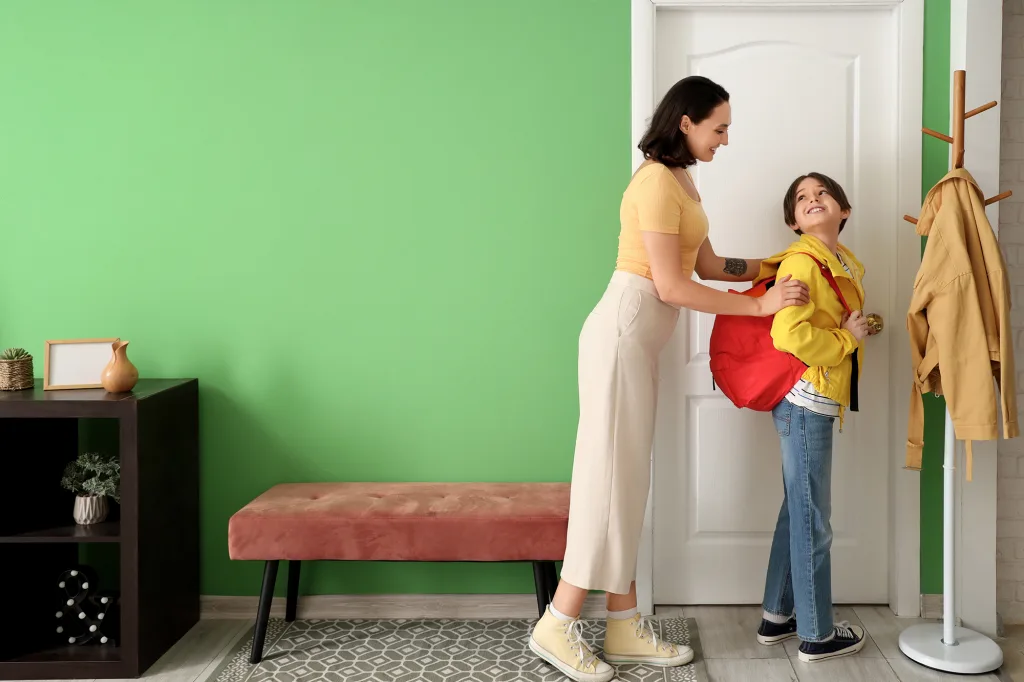 Mother getting her little son ready for school in hallway