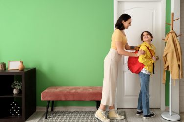Mother getting her little son ready for school in hallway