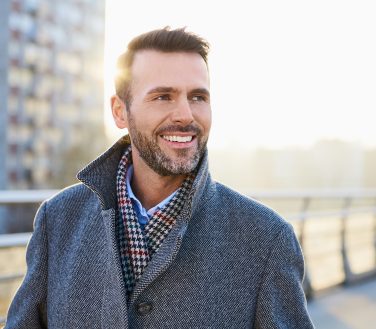 Happy man standing outdoors during sunny winter day; A SWIFT Smile The 411 On Teeth in a Day