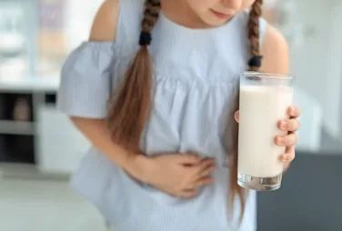 Little girl with dairy allergy holding glass of milk indoors
