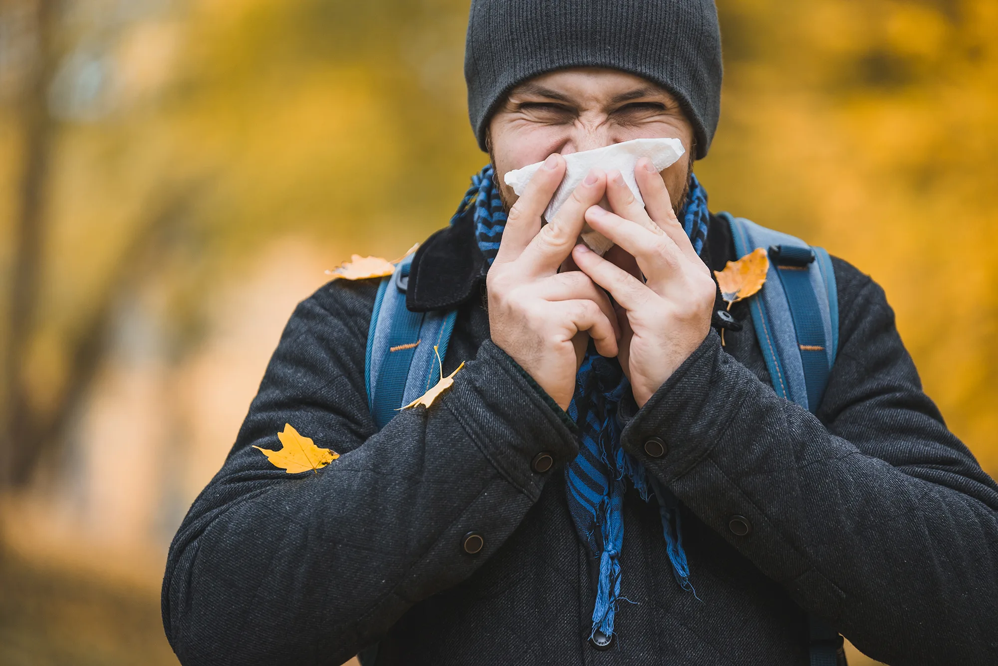 man sneezes and blows his nose in a handkerchief in an autumn;coping with fall allergies Tips for a Sneeze-Free Season By Annette Brooks