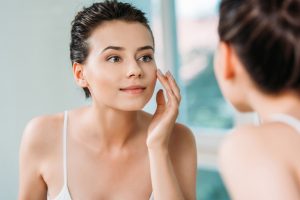 beautiful smiling young woman touching face and looking at mirro Preventive Botox A Modern Approach to Aging Gracefully beautiful smiling young woman touching face and looking at mirro