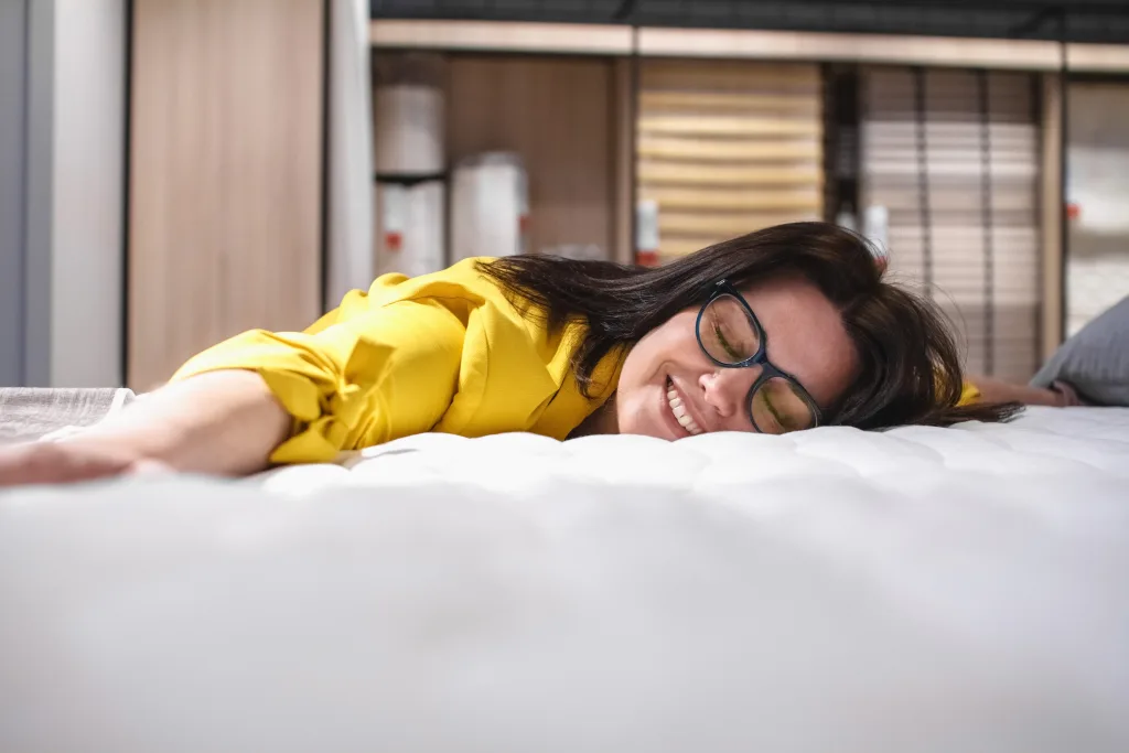 A beautiful girl is testing a new mattress before buying Portrait of a satisfied brunette lying on a new bed The concept of Healthy sleep