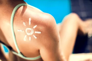 Woman with sun protection cream on her shoulder in the shape of sun. Summer, healthcare and vacation concept