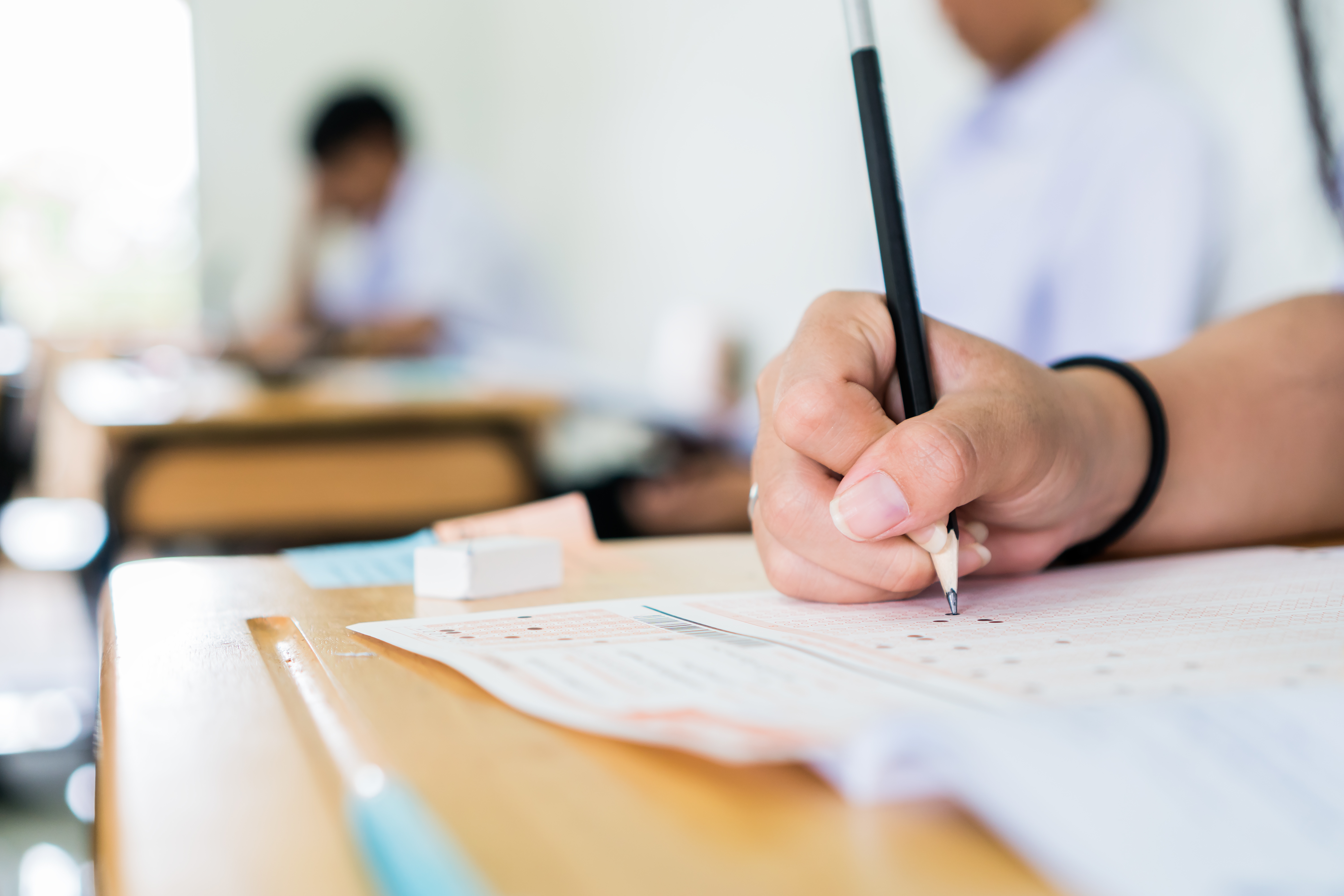 High school university student holding pencil writing exam on paper ...