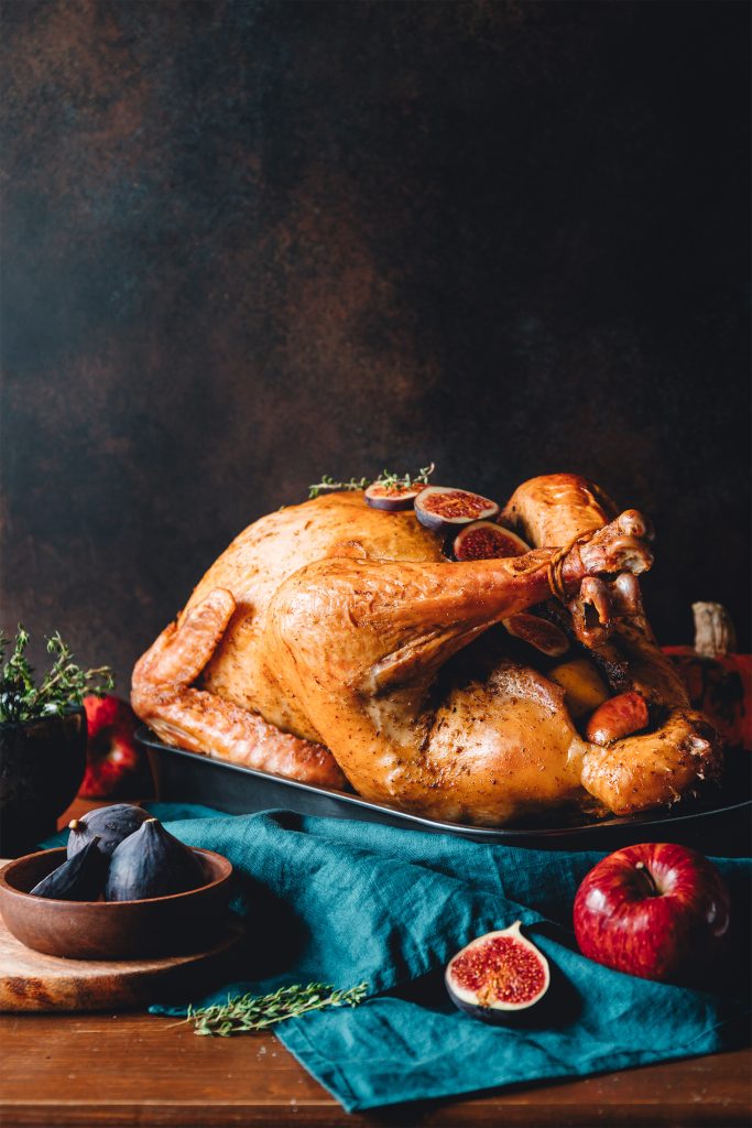 Roasted whole turkey on a table with apple, pumpkin and figs for family Thanksgiving Holiday