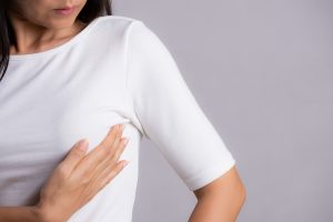 Woman hand checking lumps on her breast for signs of breast canc Woman hand checking lumps on her breast for signs of breast canc