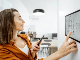 Young woman controlling home with a digital touch screen panel installed on the wall in the living room Concept of a smart home and mobile application for managing smart devices at home automated abode More Homeowners are Getting Smart