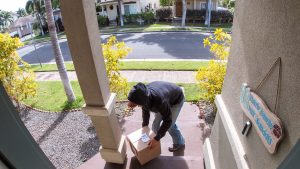 Package thief caught on video doorbell system stealing a box delivery from the front step of a suburban home