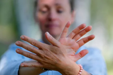 Woman practicing Qi Gong or Tai Chi exercise in nature Close up on hands