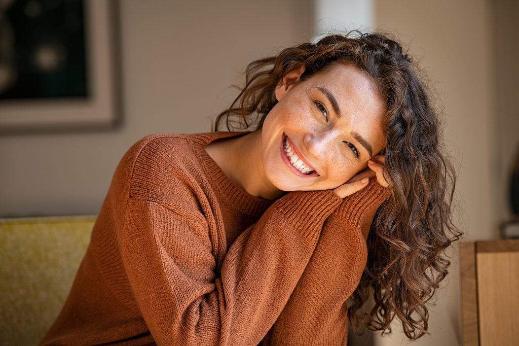 Young woman laughing while relaxing at home Young woman laughing while relaxing at home; a gorgeous grin Tips for a Successful Smile Makeover