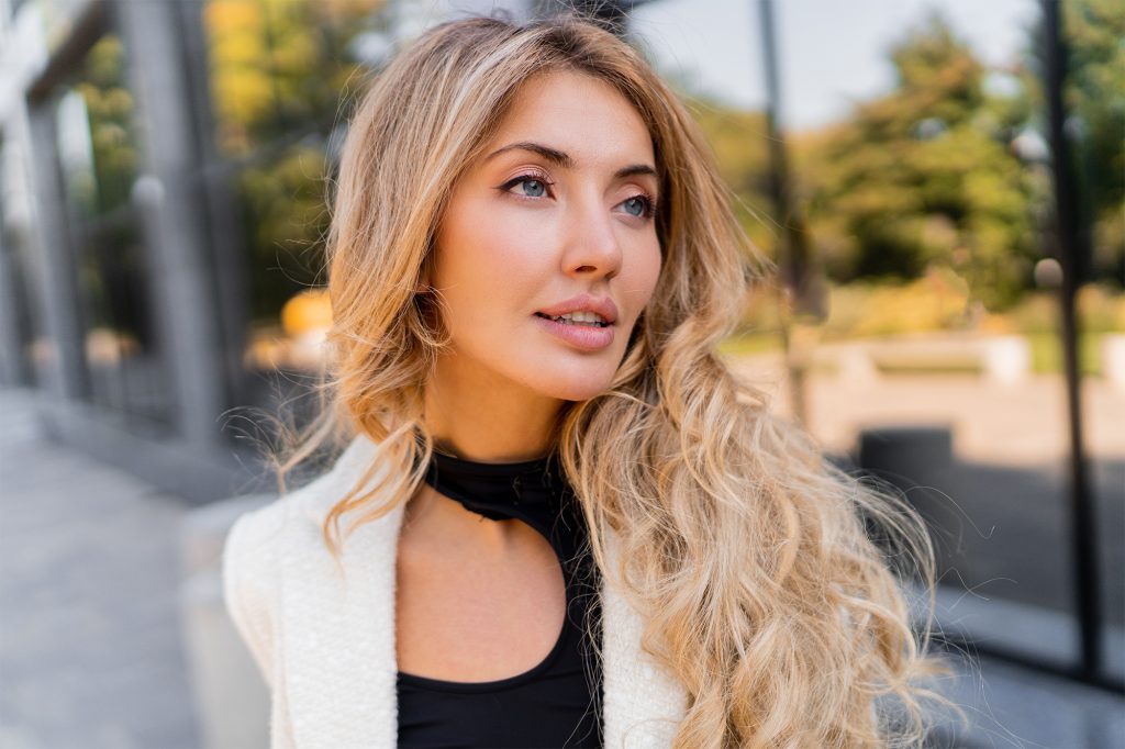 Close up portrait of stylish pretty blond woman with perfect wavy hair; lip service Augmentation, Lifts, Fillers, And More