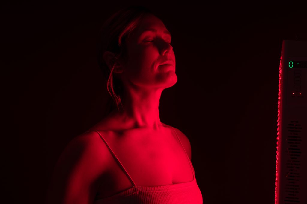 Woman getting red light therapy from a red light device Woman getting red light therapy from a red light device