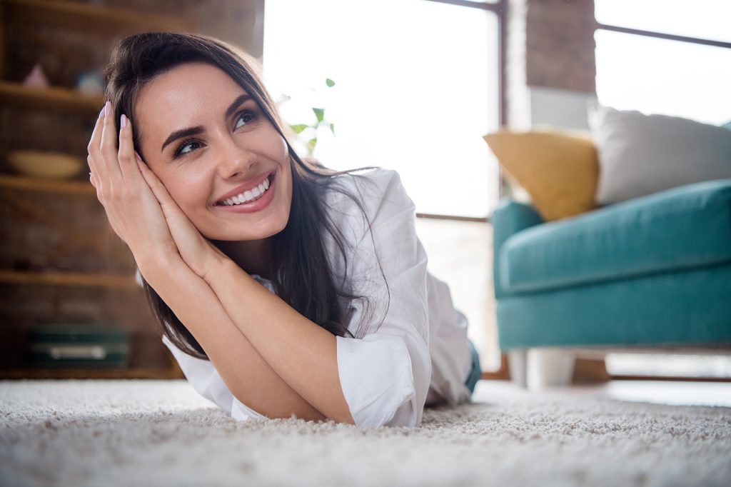 Portrait of nice thoughtful mind lady lying carpet enjoy her new house with big windows sun shine bright comfort