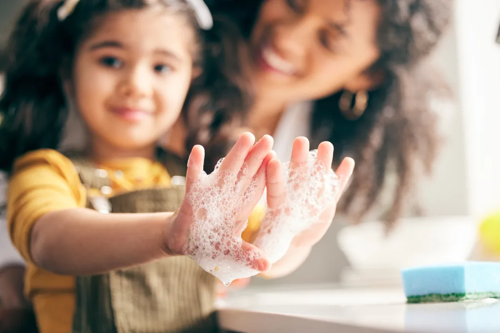 Soap, cleaning hands and family with child in bathroom for learning healthy hygiene routine at home Closeup, mom and girl kid washing palm with foam for safety of bacteria, dirt or germs on skincare cold and flu season winter