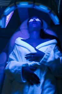 Vertical portrait of female patient undergoes blue LED light therapy for skin rejuvenation at modern aesthetic clinic Using phototherapy device with blue light wavelength Vertical portrait of female patient undergoes blue LED light therapy for skin rejuvenation at modern aesthetic clinic Using phototherapy device with blue light wavelength