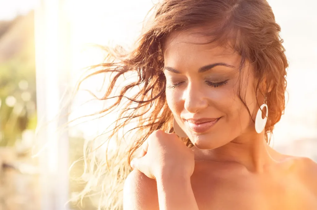 Closeup Of Smiling Young Woman With Eyes Closed At Sunset