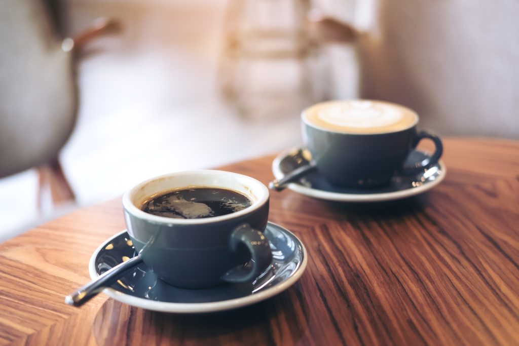Closeup image of two blue cups of hot latte coffee and Americano