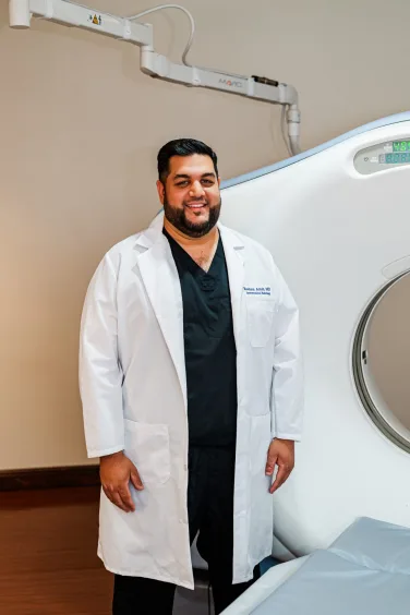 Baylor Scott & White Medical Center – Lake Pointe doctor, Roshon Amin, MD stands near new LDCT Low-Dose CT Scan machine