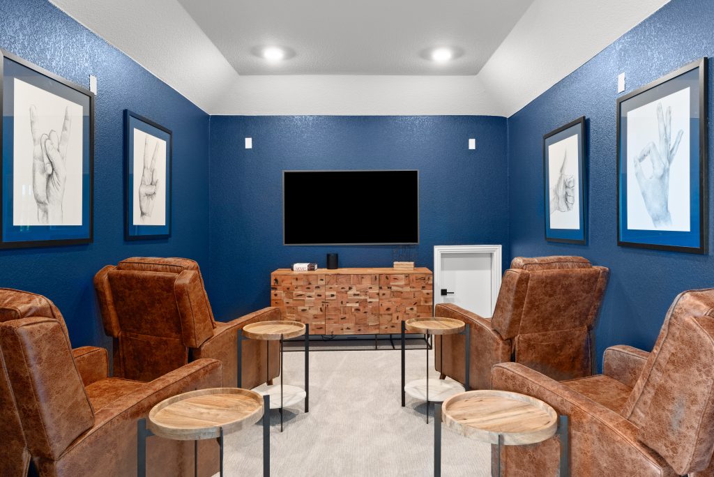 A blue media room with leather chairs and a tv.