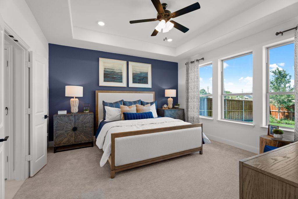 A bedroom with blue accent wall and a ceiling fan.