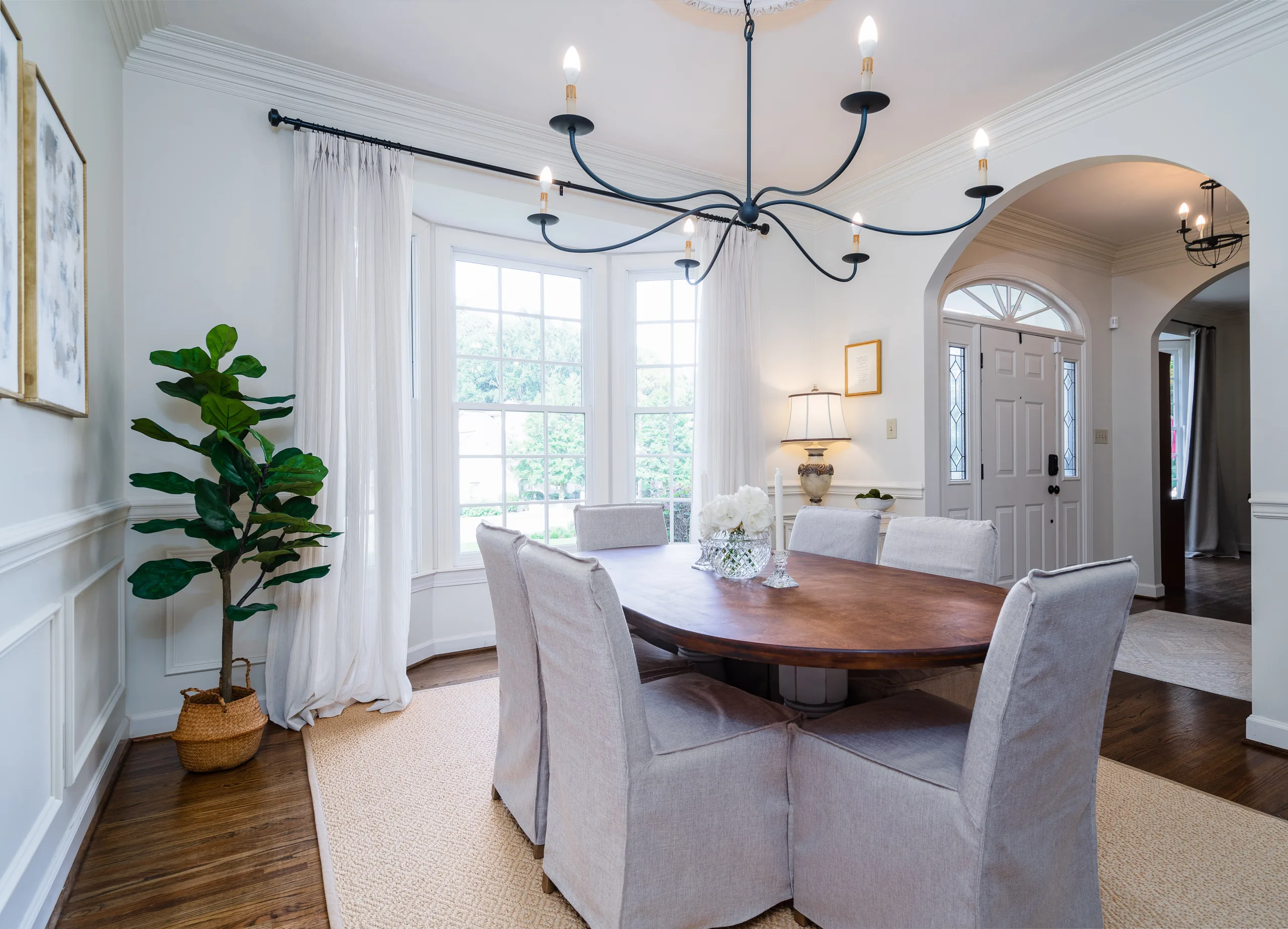 Neutral dining room with 6 light chandelier and arched doorway